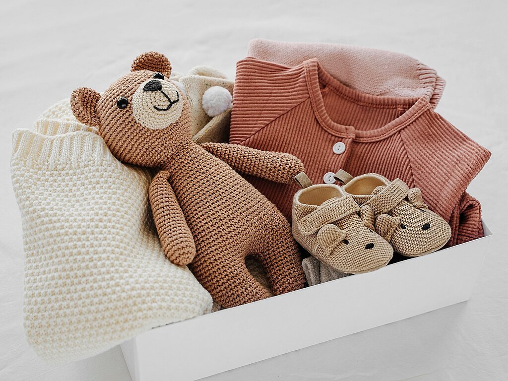 Box with baby stuff and accessories for newborn on bed. Gift box